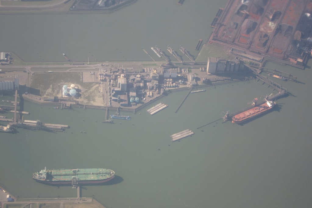 Aerial view of Rotterdam's industrial waterfront showing tanker berths, storage facilities and maritime infrastructure as interconnected components of the port landscape