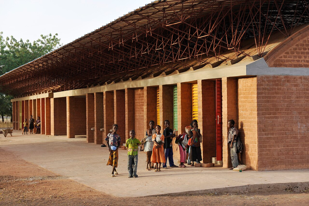 Gando Primary School extension in Burkina Faso, showing the deep roof structure, earthen walls and occupied school environment