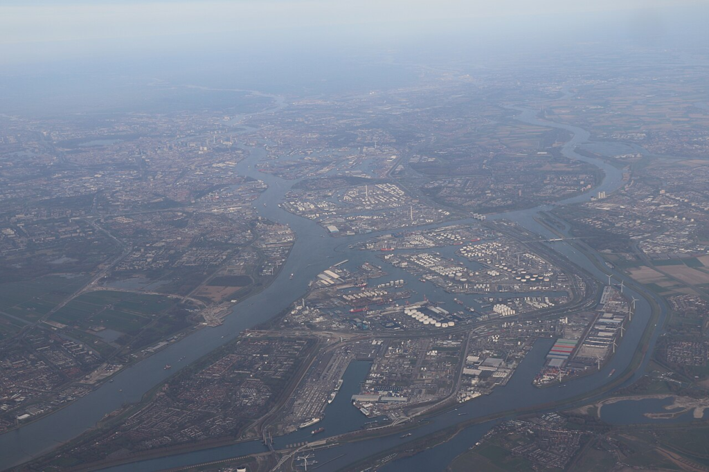Aerial photograph of Rotterdam's port-industrial landscape and adjoining waterways, showing how maritime access, industrial land and inland transport systems occupy an interconnected geographical area